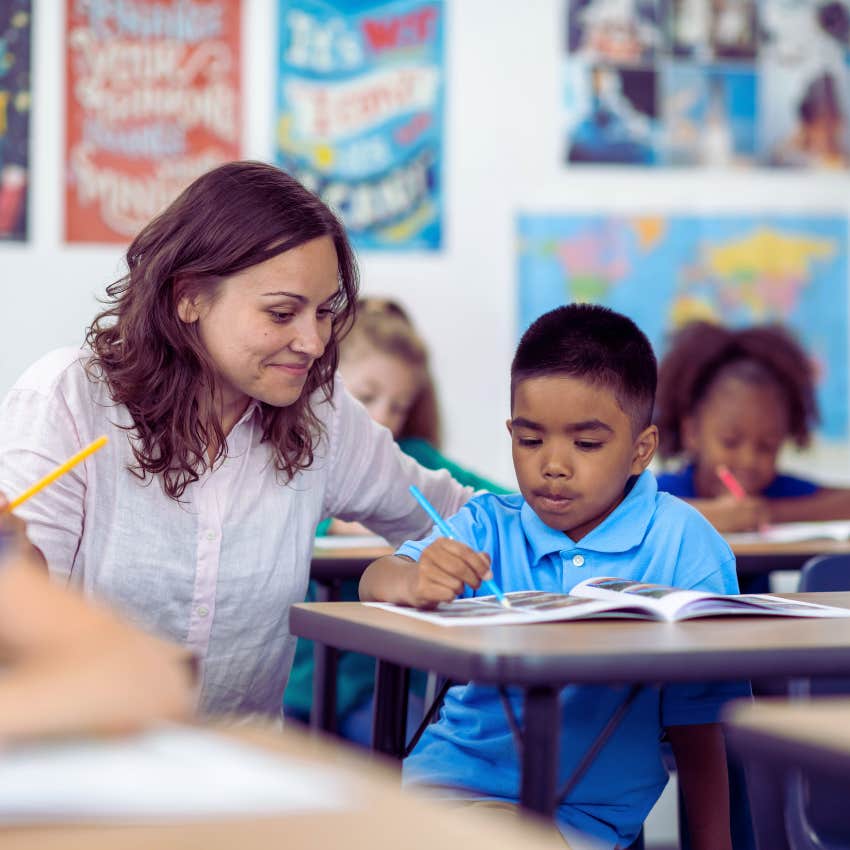 teacher helping a young student with assignment at his desk
