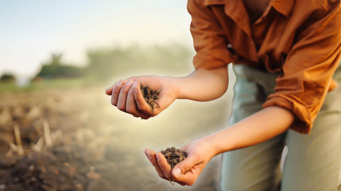 Trauma in the Land Woman touching the soil on land