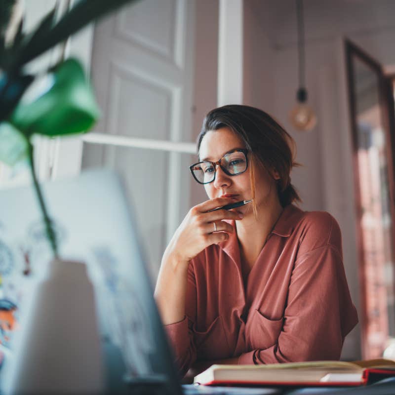 Young businesswoman thinking about something while sitting front open laptop