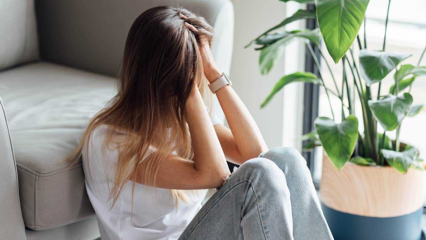 anxious woman sitting on the floor with head in her hands