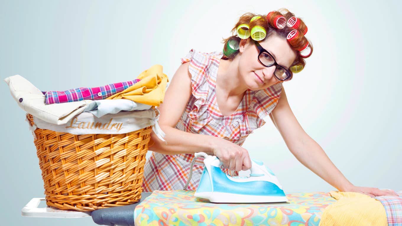 Wife Tells Husband He's Too Broke To Be Sexist comical depiction of traditional housewife ironing clothes with curlers in her hair