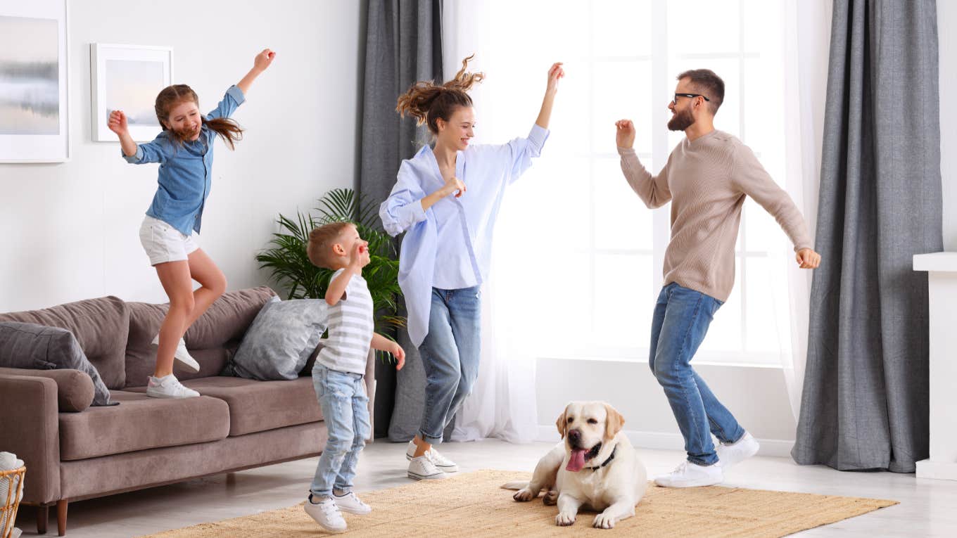 Airbnb Host Asks Guests To 'Leave Immediately' After They Brought Their Dog Despite The 'No Pet' Policy family of four jumping and dancing in living room with dog