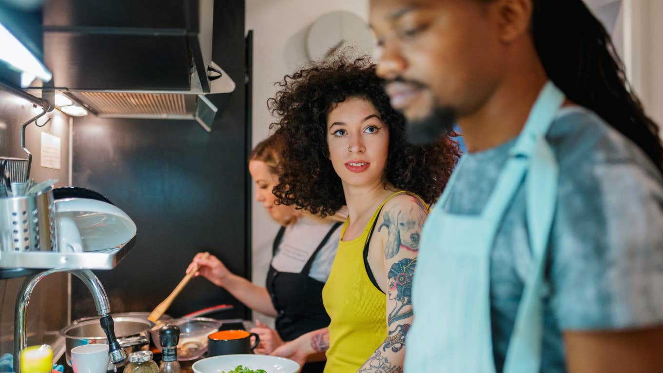 Man Tells His ‘Picky’ Roommate He Doesn't Cook For Her, He Cooks For Him And His Girlfriend woman glances over at roommate while cooking meal together in kitchen