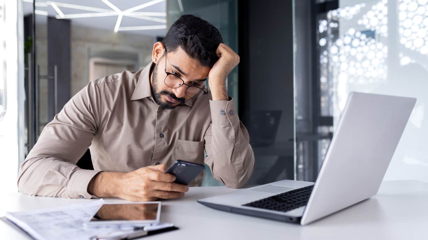 Boss Fires Employee Via Text And Says He Won't Receive Final Check Because Company Doesn't Have The Money Yet upset businessman at workplace inside office reading bad news on phone