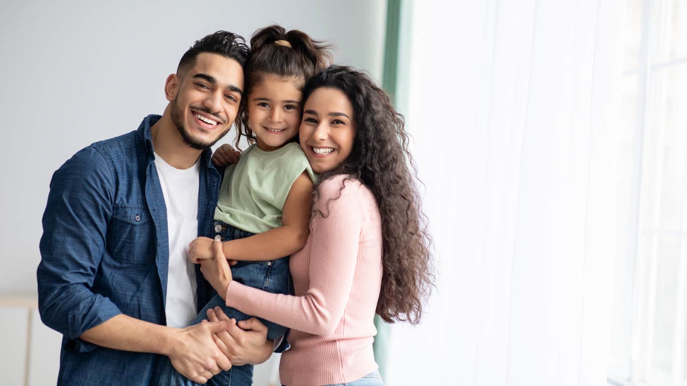 5 Examples of Generational Wealth That Have Nothing To Do With Money mom and dad holding their daughter