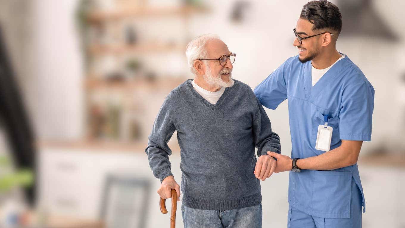 Healthcare Worker Gets Scolded By A Boomer For Working 3 Days A Week Healthcare worker helping a boomer walk in his home.