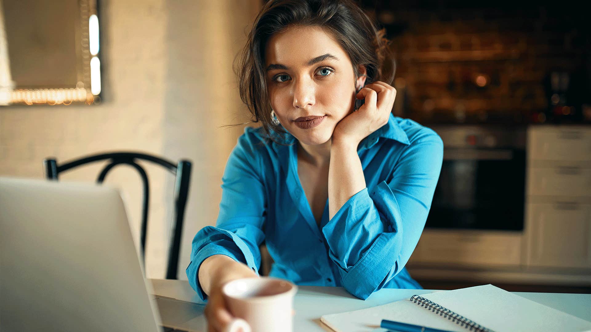 woman sitting at table holding a cup of coffee