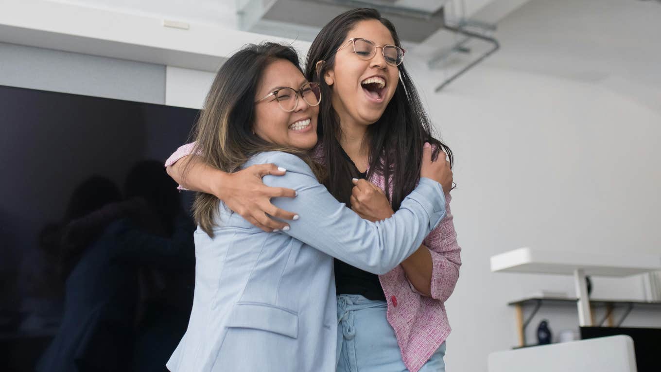 Nearly Half Of Women Say They Need Close Friends At Work To Build Successful Careers two female employees laughing and hugging
