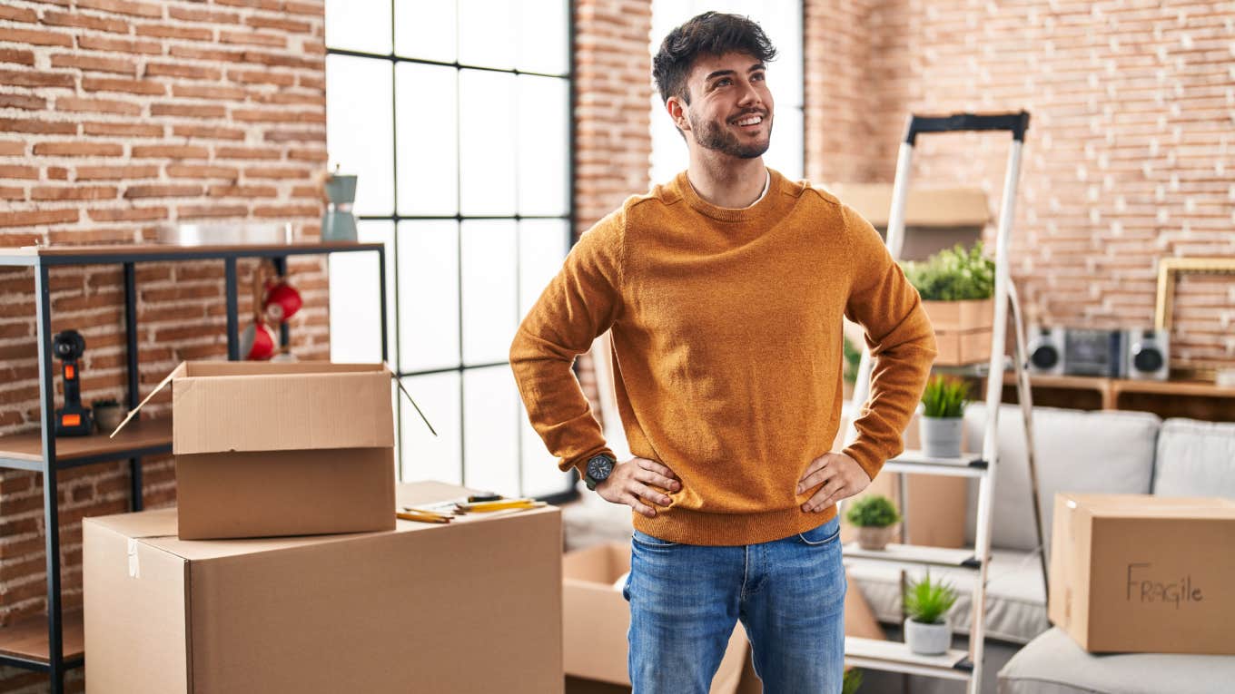 Parents Give Their Adult Son Money To Buy A House But Still Want Him To Pay Interest Young man smiling and standing in new home surrounded by cardboard boxes