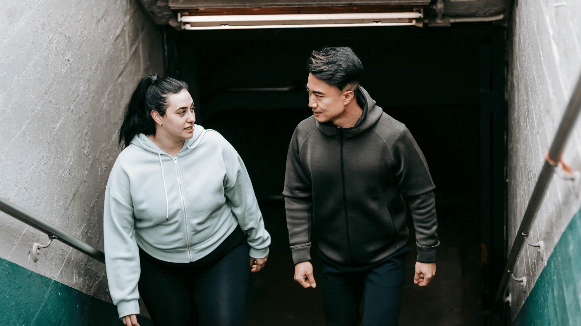 man and woman walking up subway steps