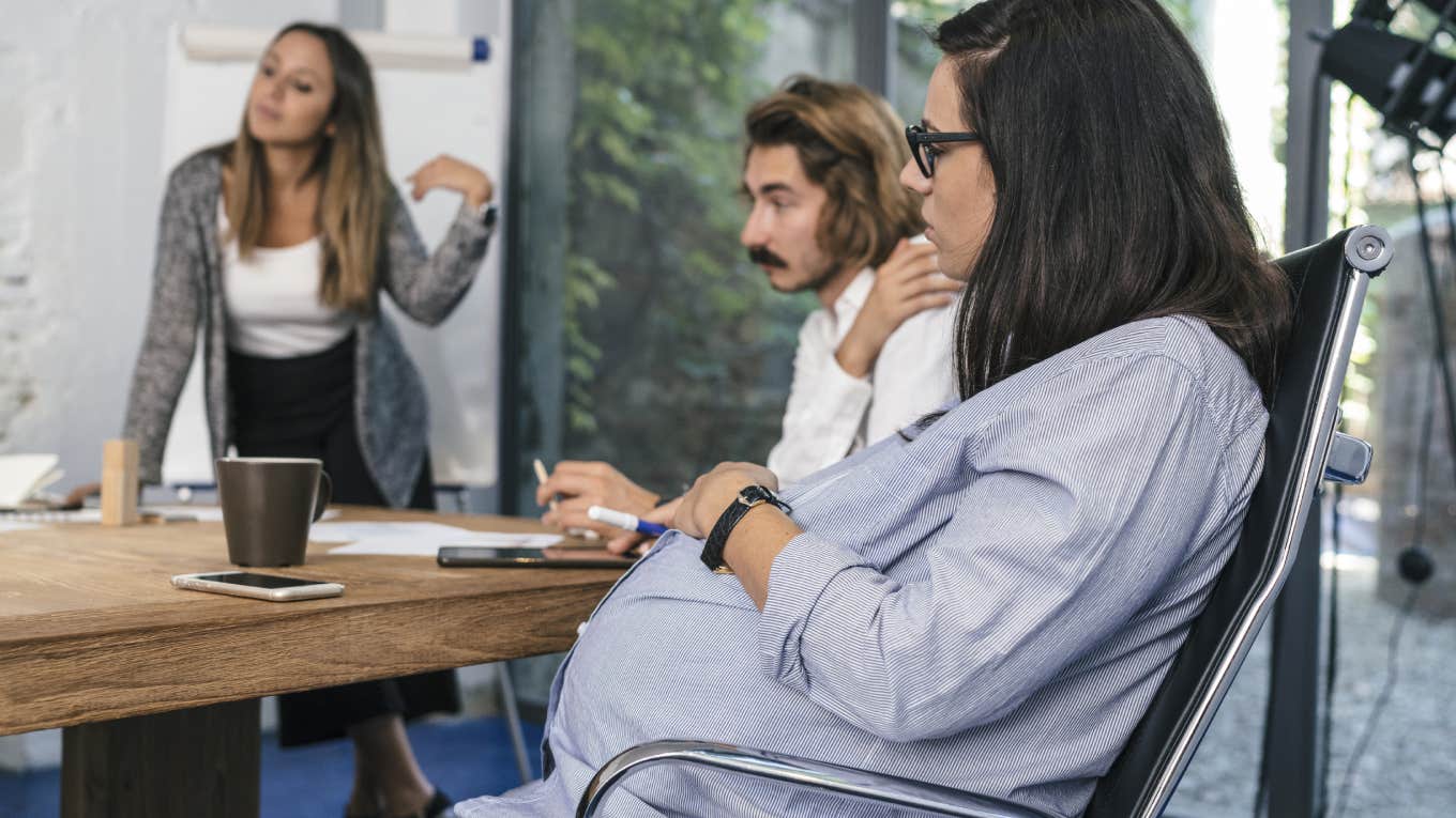 Pregnant Woman Wants To Report Her Boss For Forcing Her To Attend A Meeting While She Was In Labor pregnant woman sitting in meeting at work with coworkers