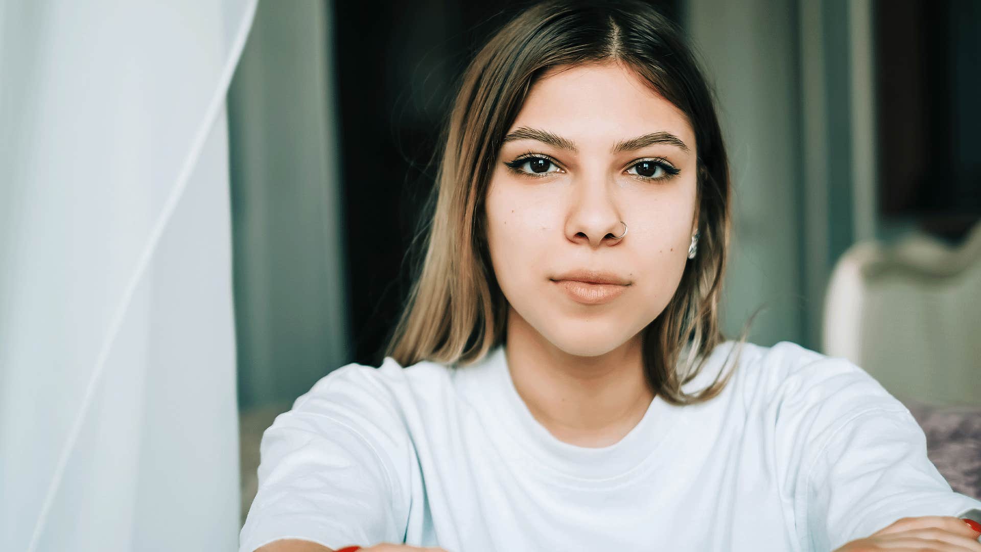 woman in white shirt looking serious at the camera