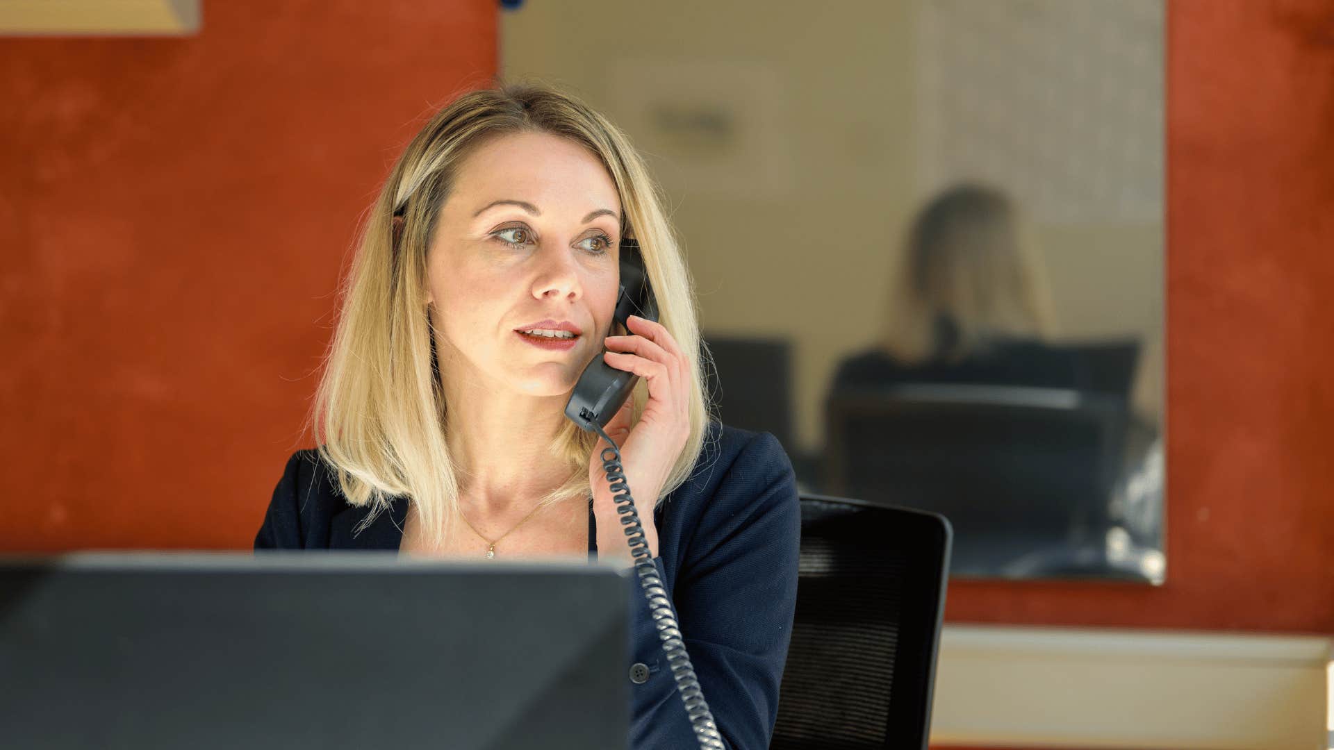 woman working at desk with mirror behind her