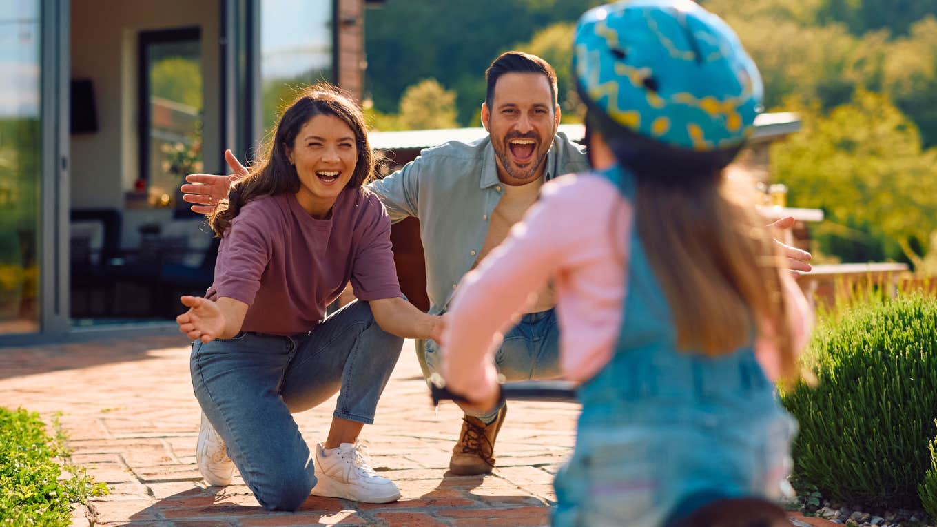 The Secret To Being A Better Parent Than Your Parents Were To You happy parents watching daughter ride a bike