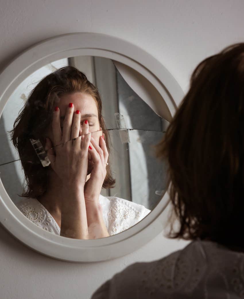Reflection of emotionally abused woman in broken mirror