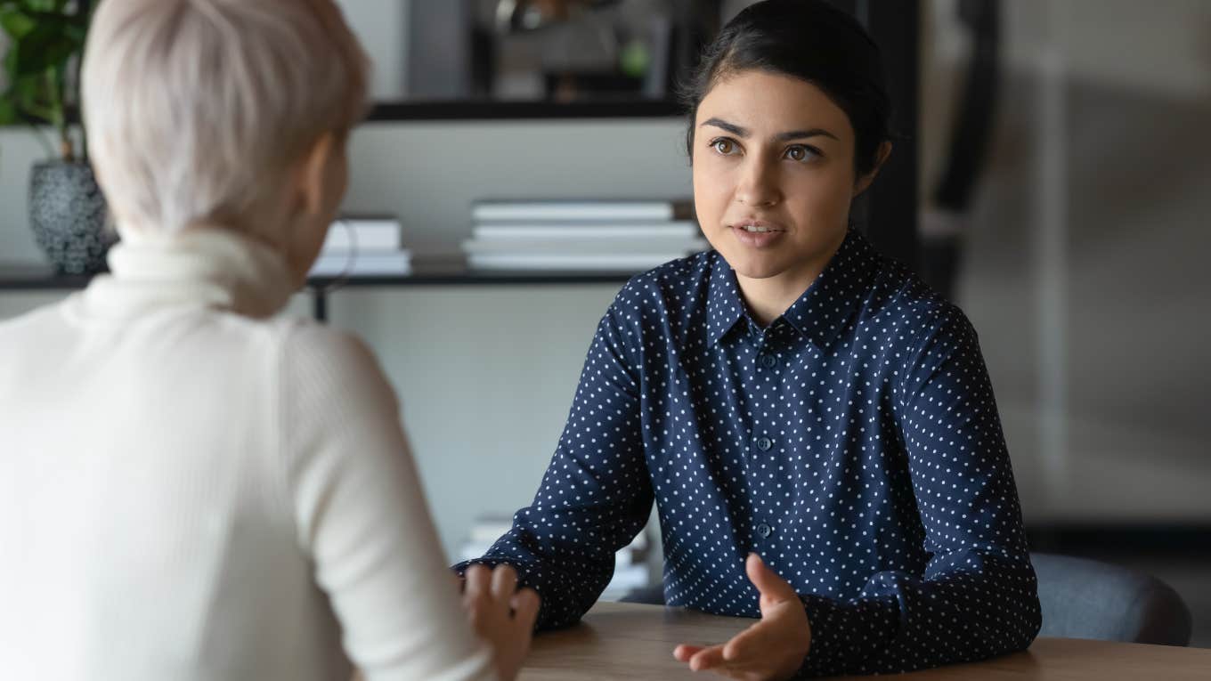The Words That Make People Think You Are Low Status two women having a conversation at work