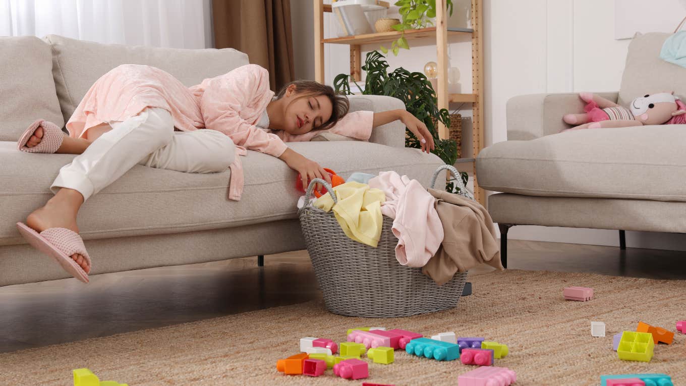 Reasons Women Get More Overwhelmed By A Messy Home stressed woman laying on couch surrounded by toys and laundry