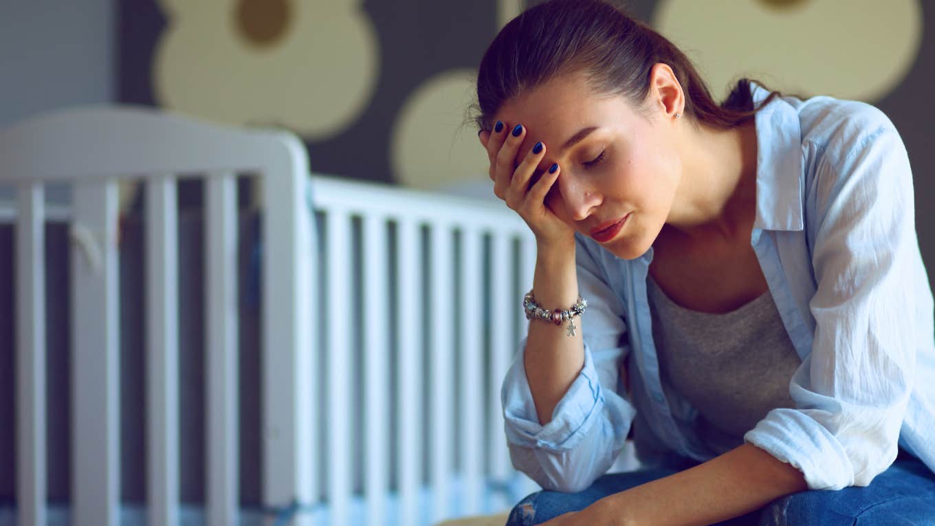 Wife Says Her Partner Has Completely Checked Out And Doesn't Want To Be Responsible For Their Newborn Baby frustrated woman sitting near crib