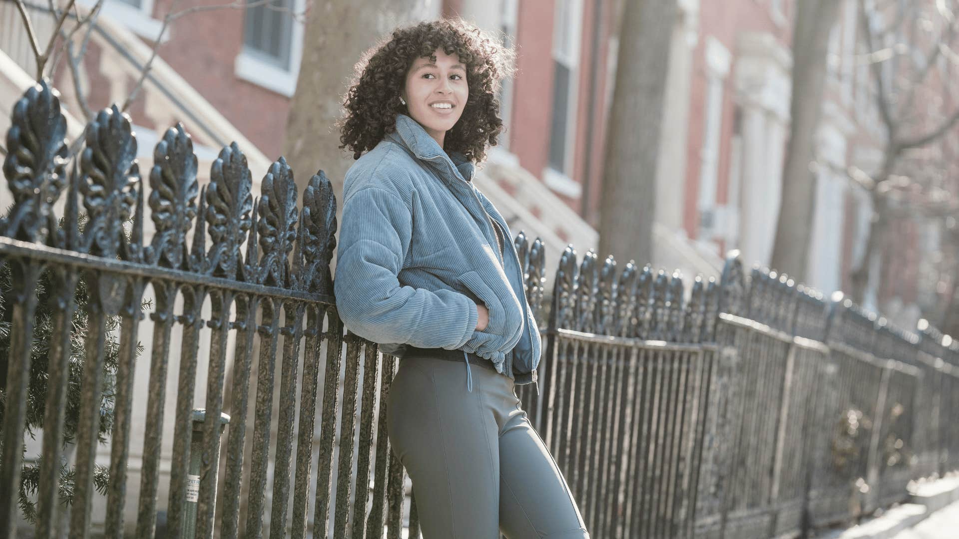 smiling woman leaning against fence