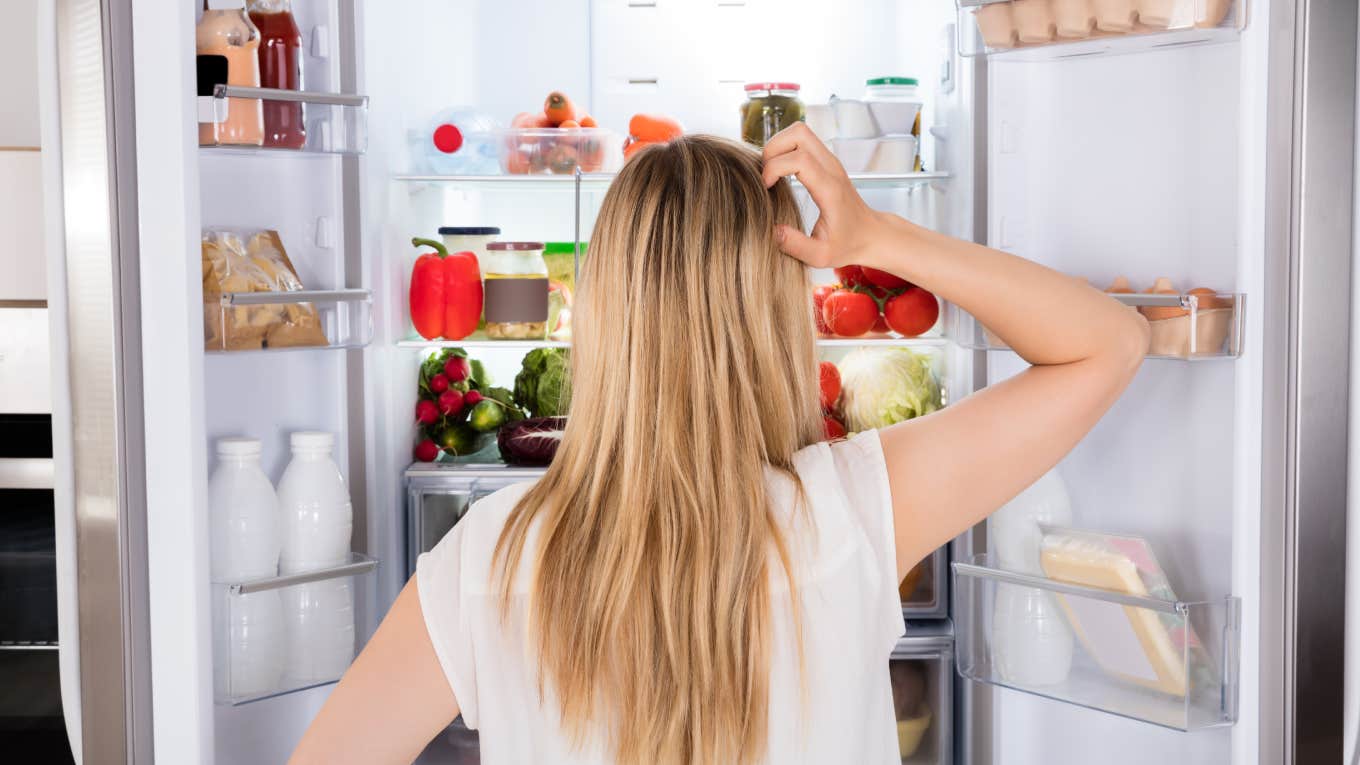 Daughter Shares The Disgusting Display Of Wealth She Found In Her Parents' Refrigerator Rear View Of Young Woman Looking In Fridge At Kitchen