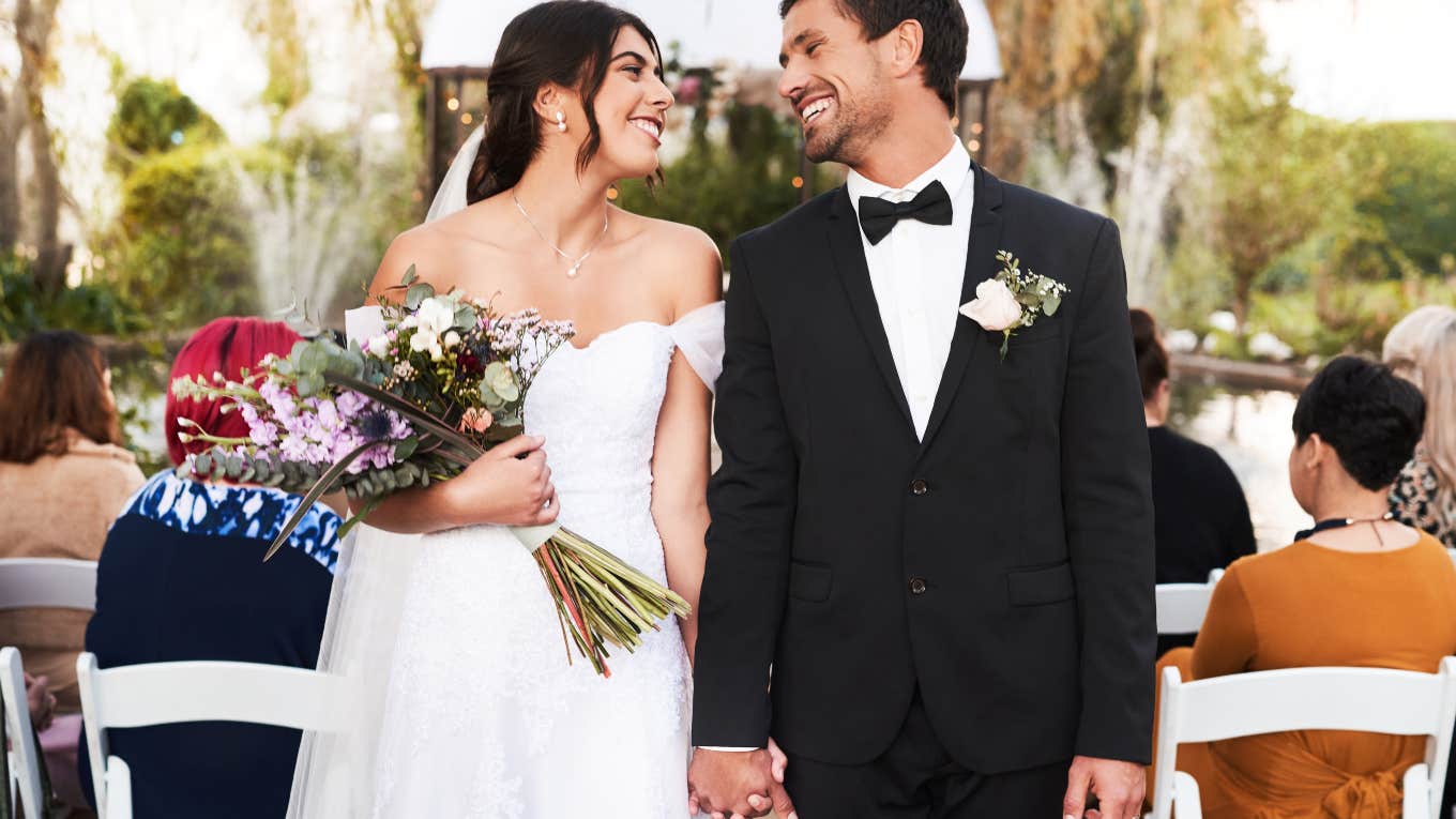 Brother Gives A Smaller Wedding Gift To One Of His Sisters just married couple smiling at each other at the end of the aisle