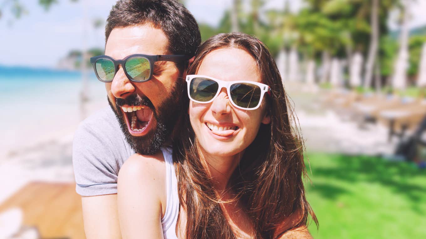 Therapists reveal quick way to damage relationships Happy couple by a beach, doesn't realize the damage in their relationship