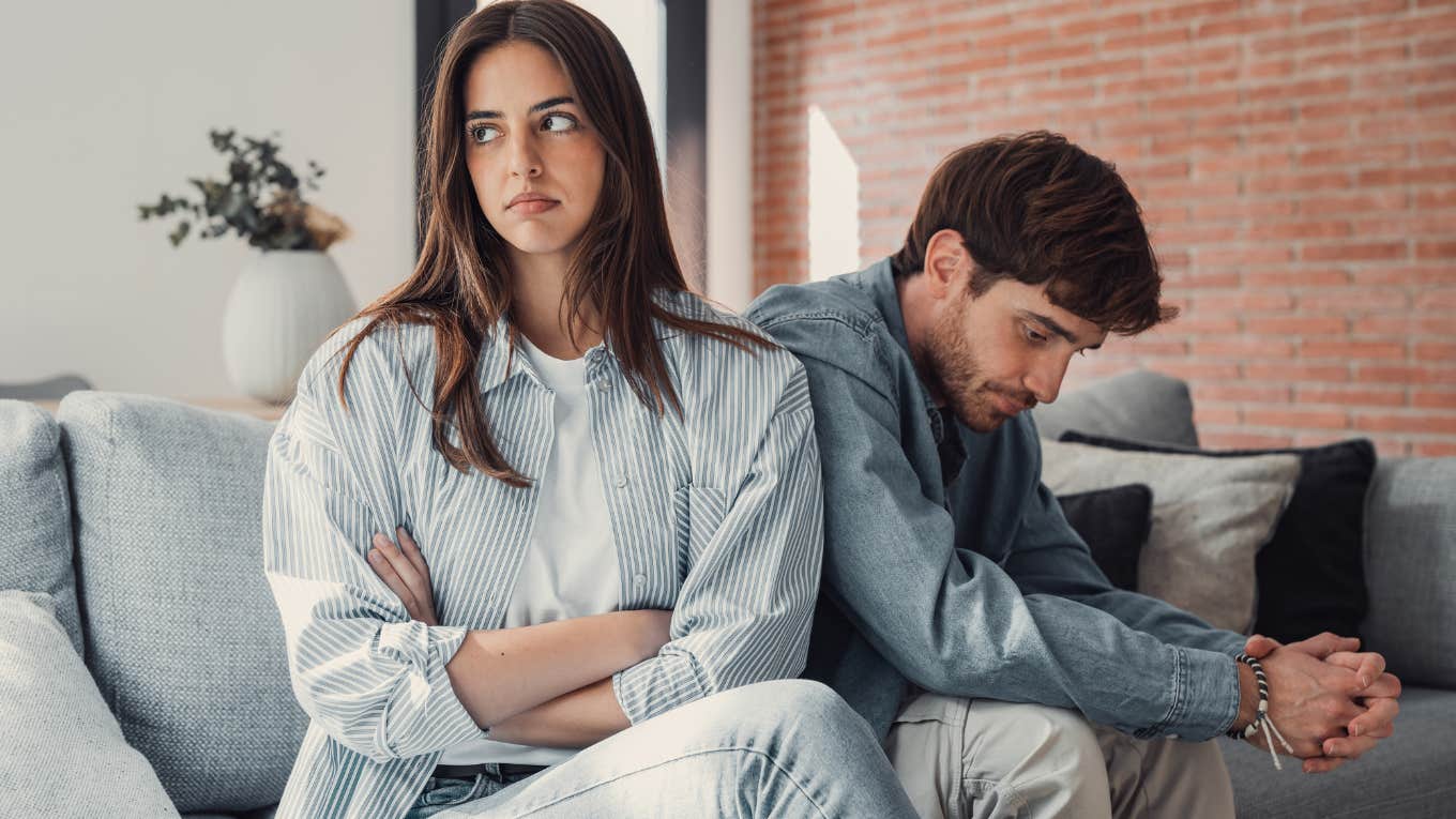 Man Feels ‘Pressured’ After Girlfriend Suggests They Move In & Get Married To Save $30K Man sitting behind his girlfriend looking upset.