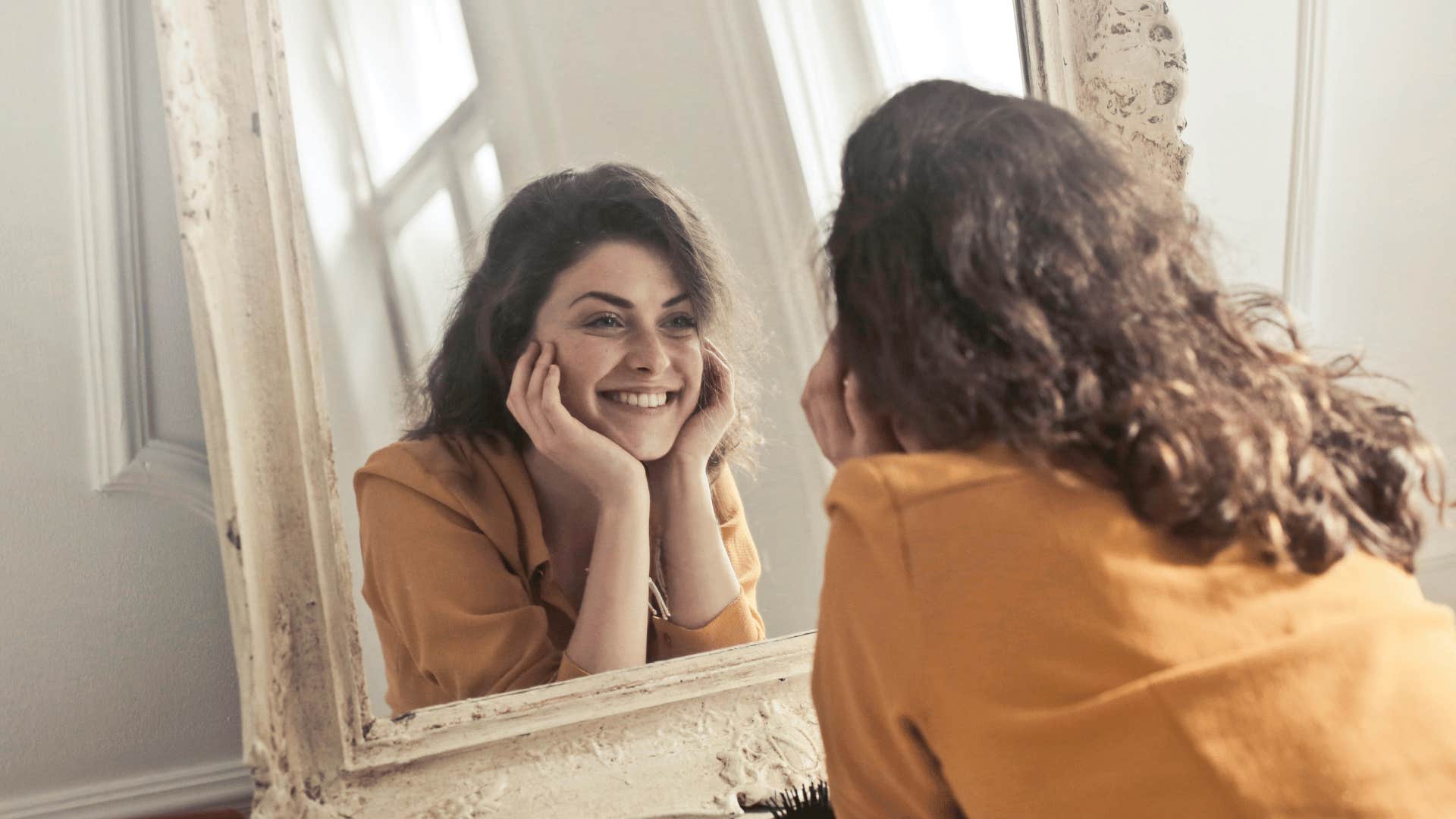 woman staring at mirror smiling 