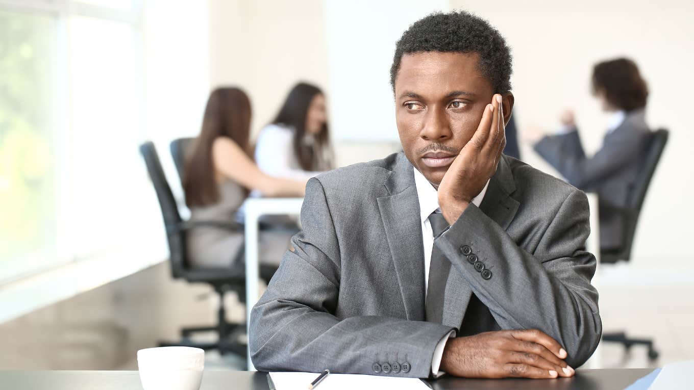 The 3 People To Ignore At Work, According To A Job Strategy Trainer Employee in a suit ignoring co-workers behind him