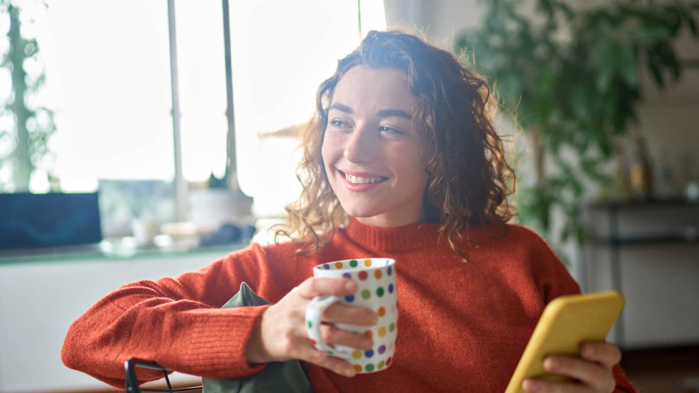 What The Universe Is Trying To Tell You When You Keep Losing Things smiling woman holding a cup of coffee and phone