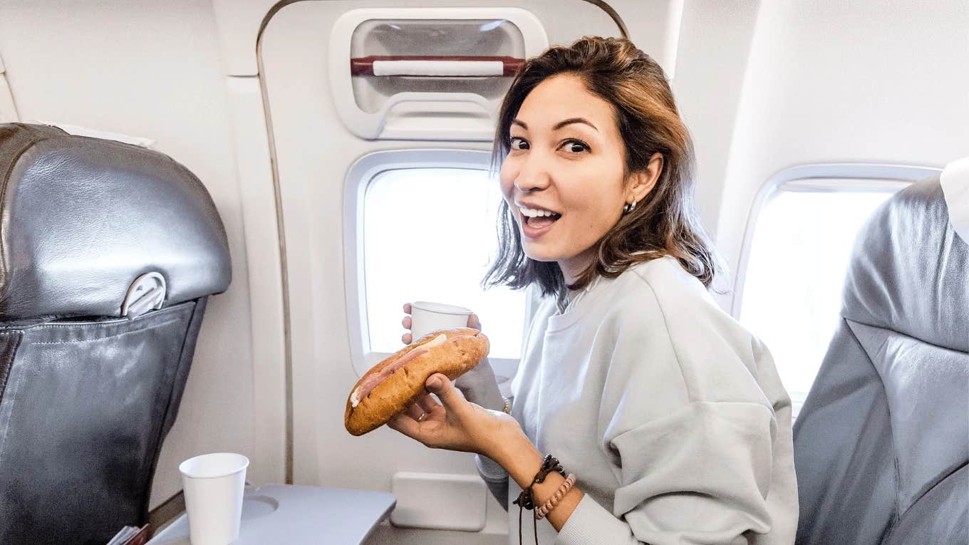 Woman Shares The 4 Foods That Should Be Banned From Airplanes Woman eating on on airplane