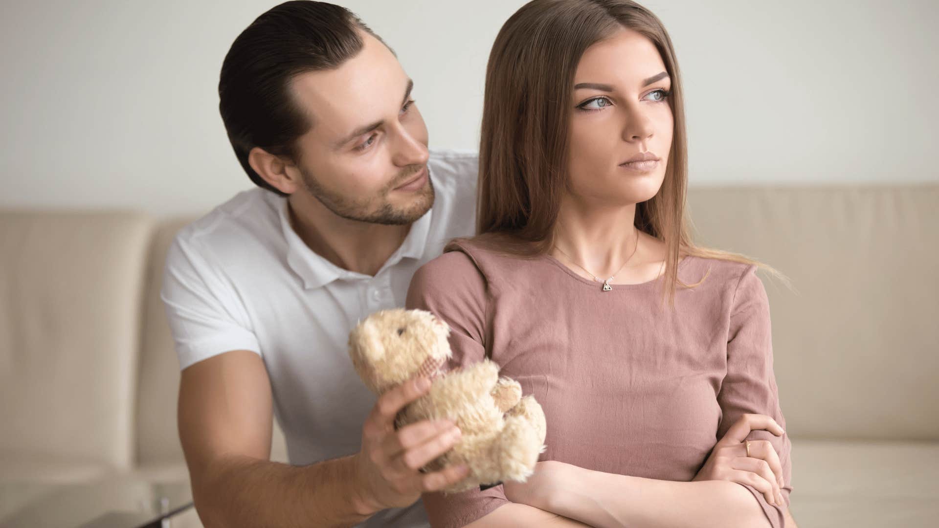 man offering a bear as an apology to upset woman
