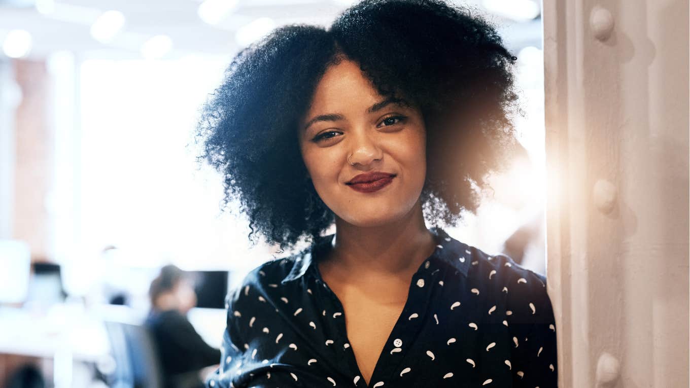 6 Signs You’re An Incredibly Confident Person, Even If You Don’t Feel It Confident woman smiling in the office.