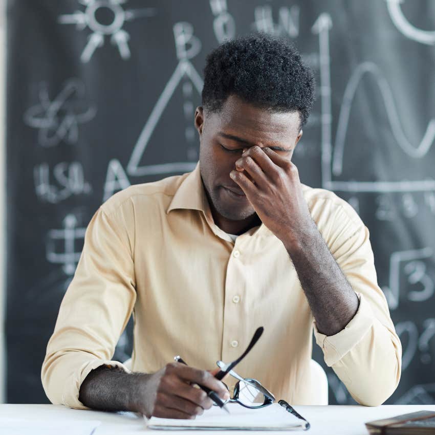 Tired school staff member looking annoyed in his classroom. 