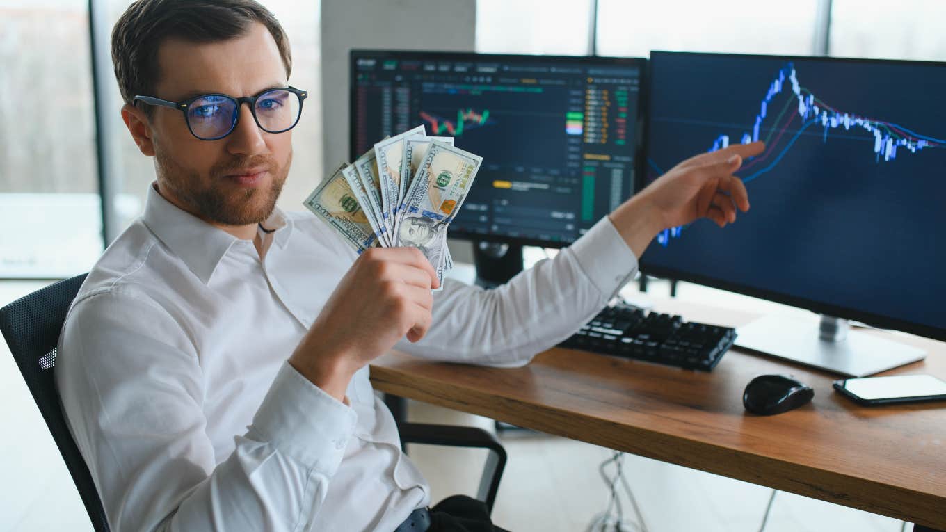 Two-Thirds Of Millionaires Don't Think They're Wealthy rich man holding money and pointing to computer projections