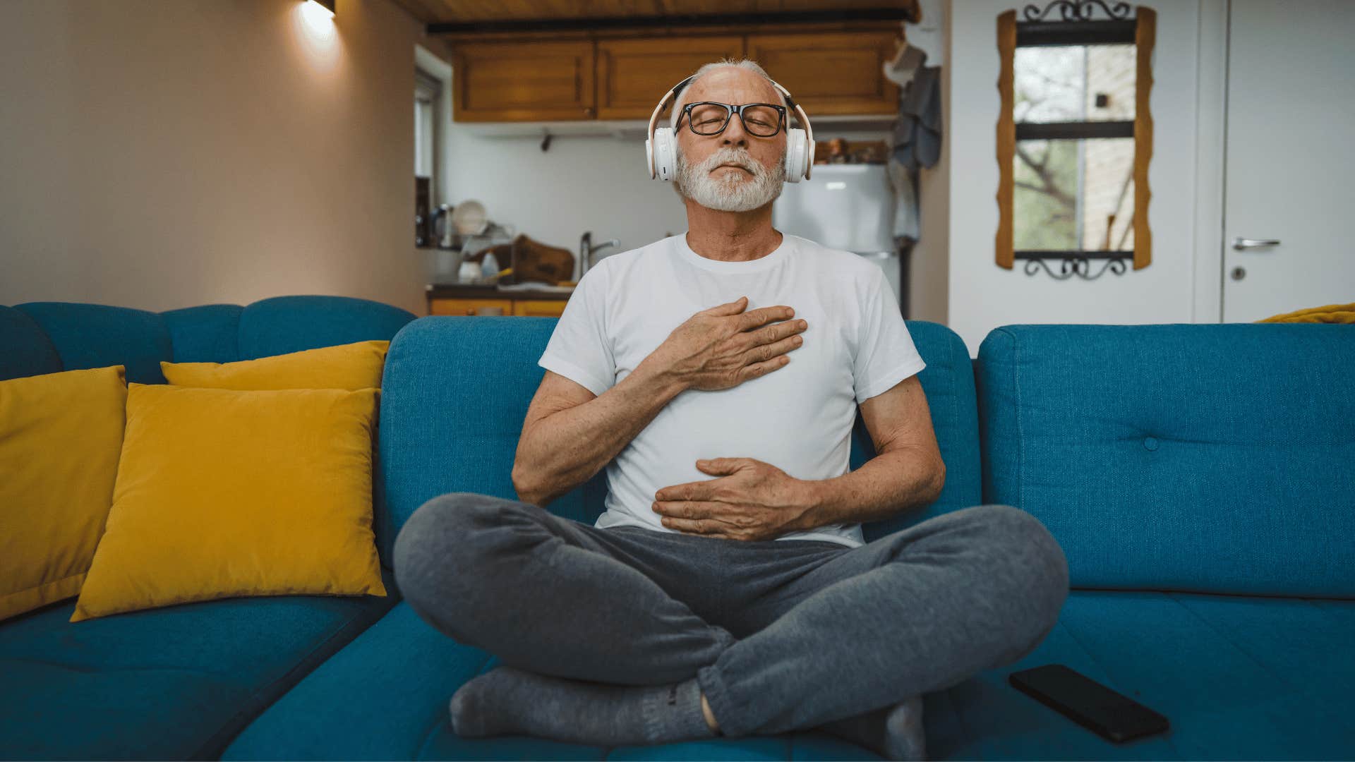 older man meditating on a couch