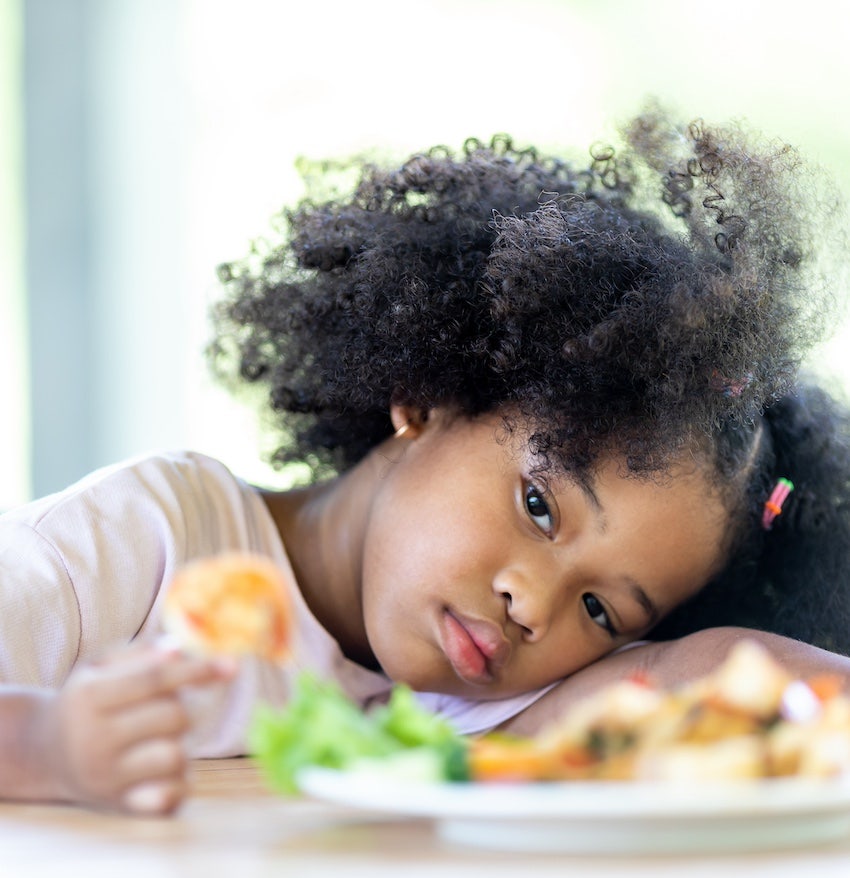 Upset girl looks at her food
