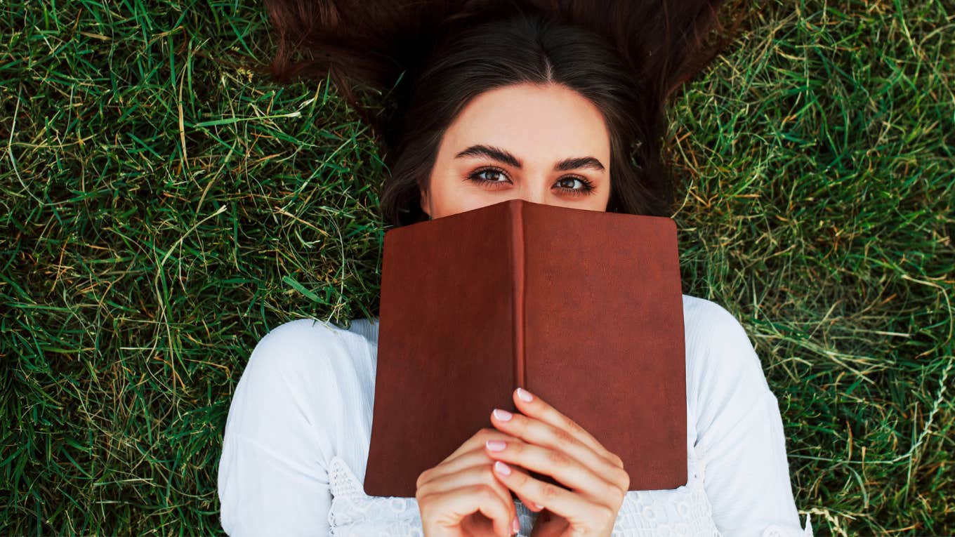 Forms Of Self-Care You Don't Have To Feel Guilty About Woman resting with a good book, grounding self in grass.