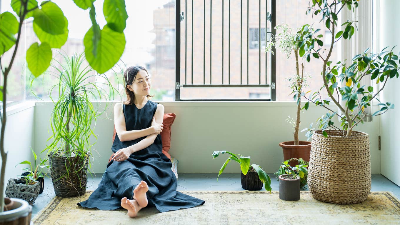 3 Plants To Never Keep Inside Your Home, According To Feng Shui Woman with plants inside of her home