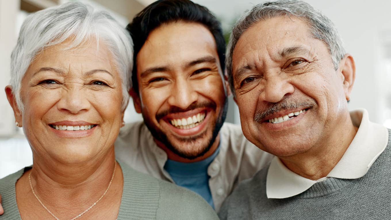 Signs You Were Raised By Emotionally Mature Parents Who Had Your Best Interests At Heart smiling man in between happy parents