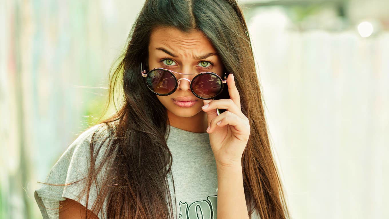 Signs You Were Raised In A Judgmental Home And It’s Still Affecting You Now woman who raised in a judgmental home looking at the camera judgmentally