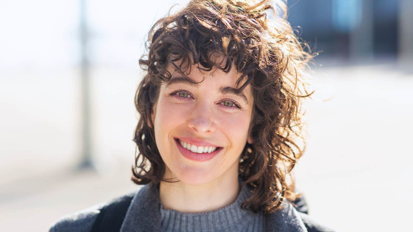 Subtle Signs You're An Intelligent And Self-Aware Outcast smiling intelligent woman standing outside
