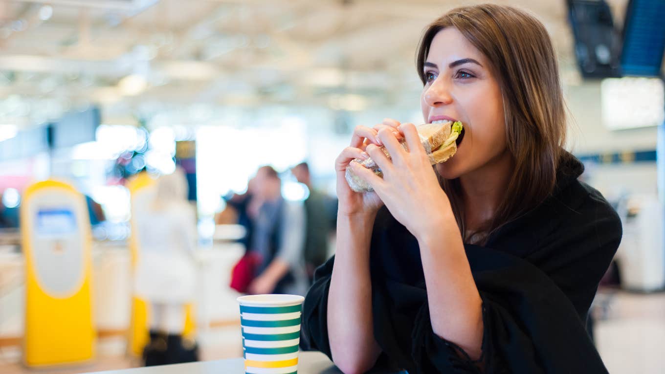 Traveler Shares 7 Snacks To Bring To The Airport If You Hate Airplane Food Traveler eating a sandwich in the airport