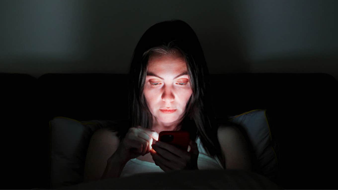 Subtle Ways An Ex Stays Embedded In Your Life, Even After You've Broken Up Woman looking at her exes social media at night before bed.