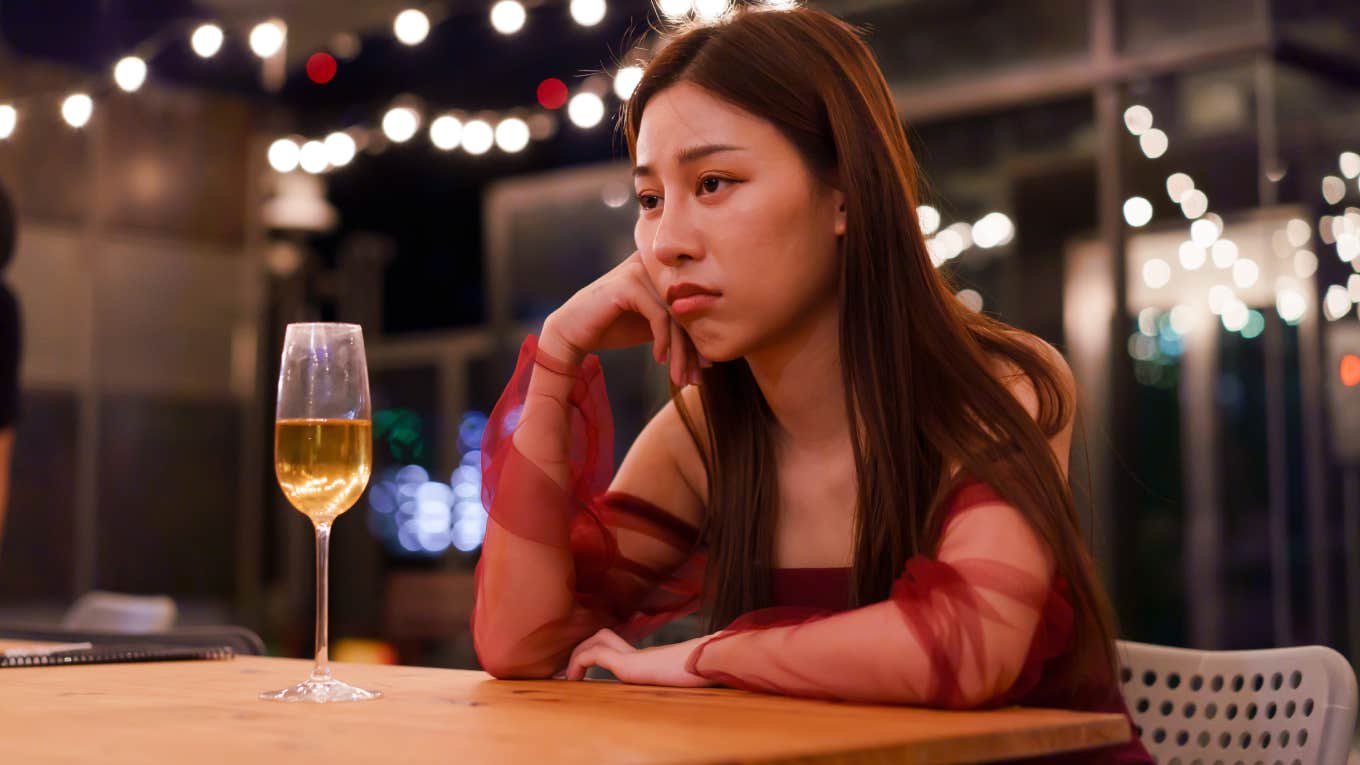 Woman Says Man Ended Their Date 2 Minutes In Because He Wasn't Feeling It sad woman sitting alone at bar with glass of wine
