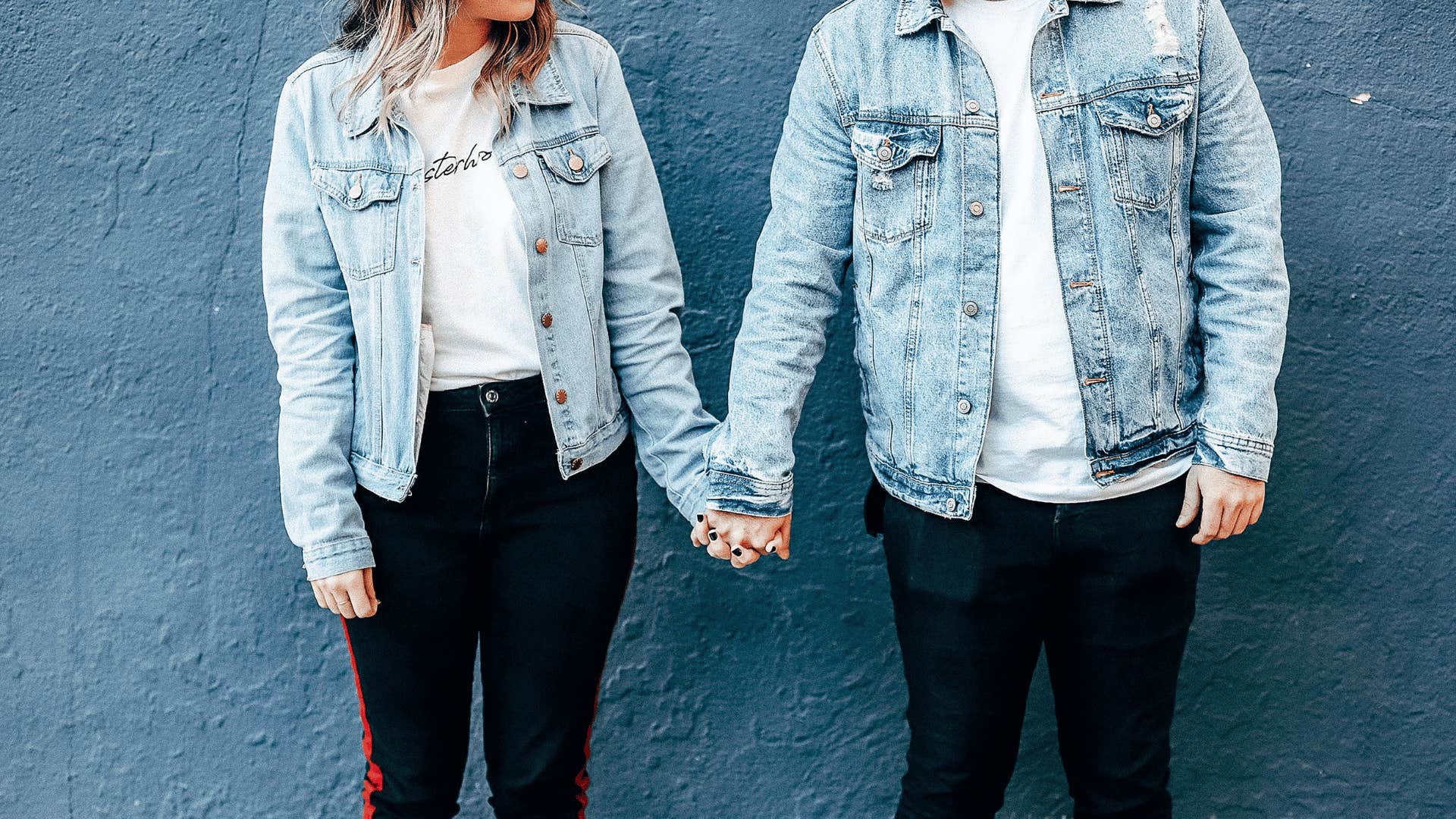 couple wearing jean jackets holding hands