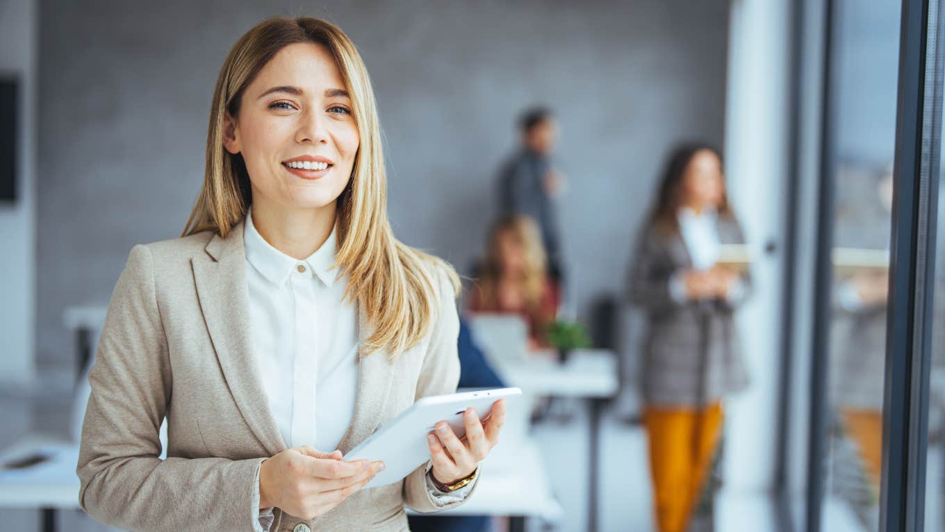 Simple Actions That Make You Look More High Status In A Work Meeting businesswoman with work meeting behind her