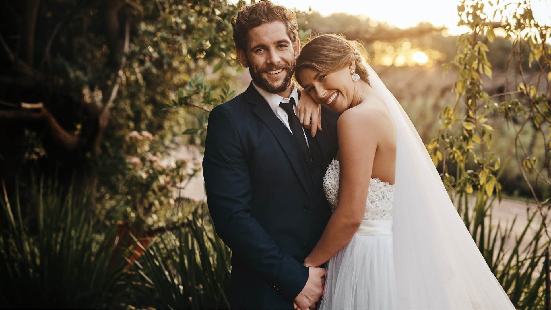 Couple smiling for a photo in their wedding attire