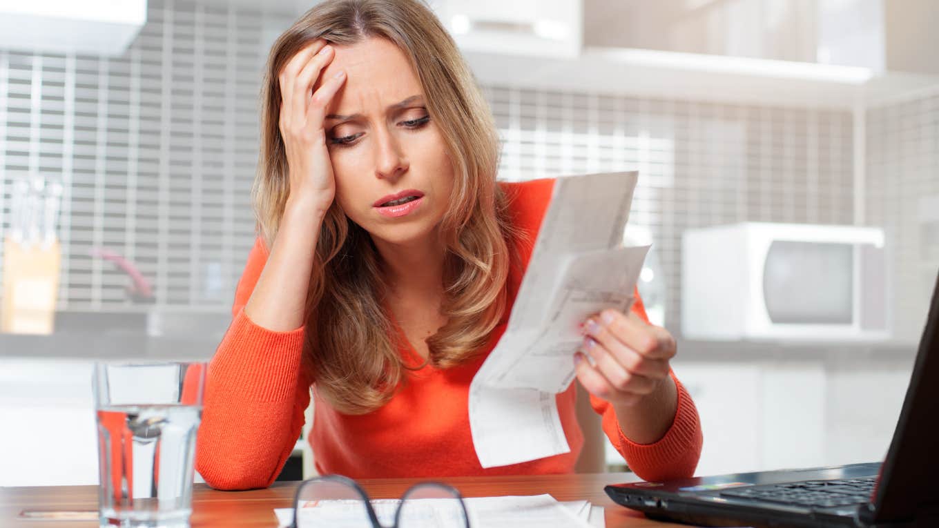 Everyday Essentials That Were Affordable 10 Years Ago That The Middle Class Can’t Afford Anymore Woman looking stressed doing bills on her laptop.