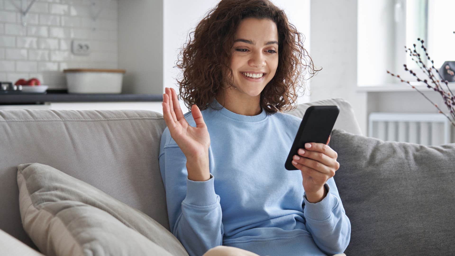 Gen Z woman smiling at her cell phone.